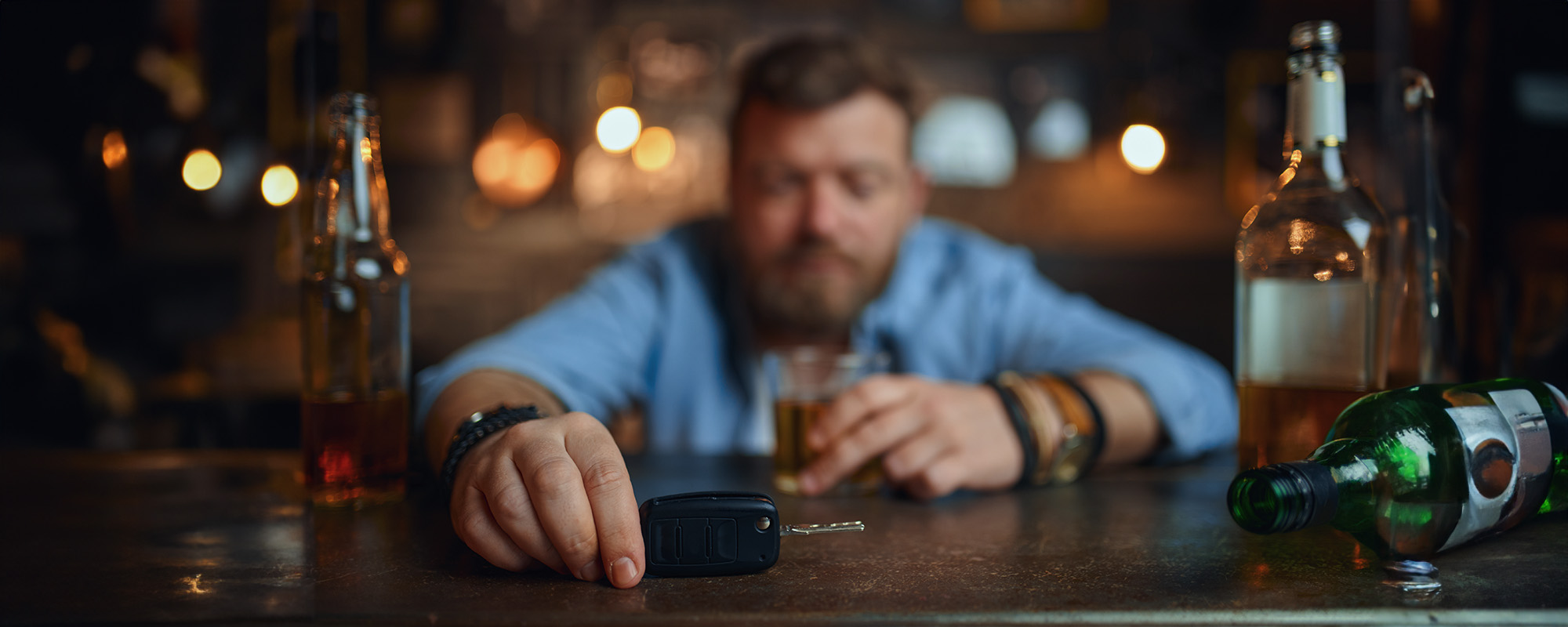 drunk man with car key sitting at counter in bar