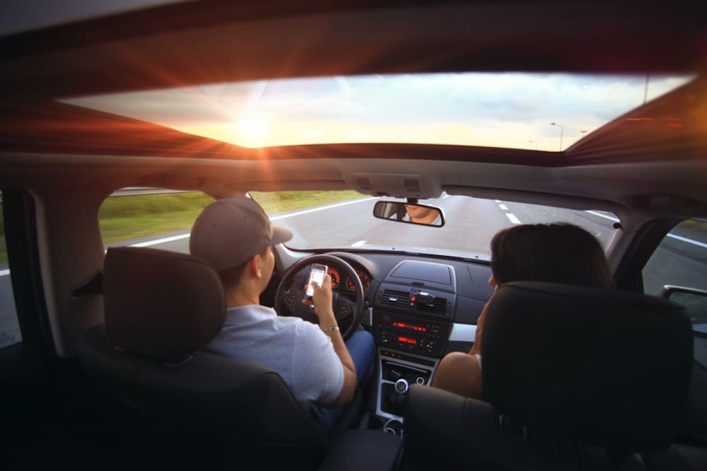 person looking at cell phone while driving