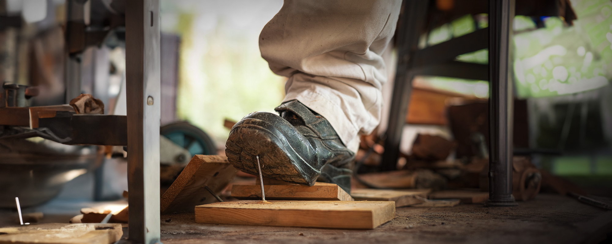 worker in safety shoes stepping on nails on board wood in the construction area copy