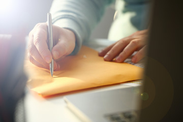 person writing on manila envelope