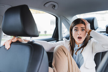 woman passenger in back seat of car looking shocked